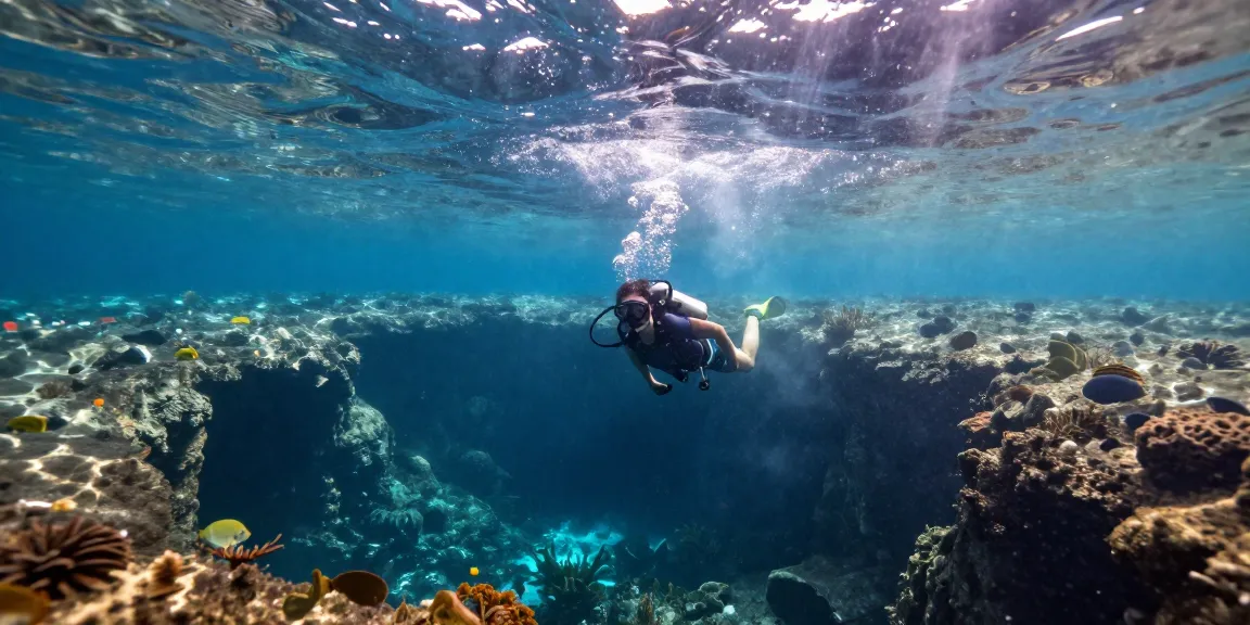 Der Taucher erkundet die magische Cenote El Pit mit Lichtstrahlen und einzigartigen Felsformationen.